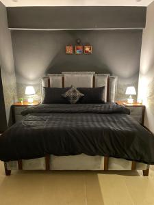 a bedroom with a large bed with two lamps at Freddy's Family Apartments in Islamabad