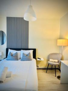 ein Schlafzimmer mit einem Bett mit blauen Kissen und einem Stuhl in der Unterkunft Cozy Place to Stay -Self check in 24h in Reşiţa