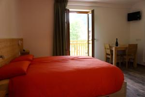 sypialnia z czerwonym łóżkiem, stołem i drzwiami w obiekcie B&B Terre Alte w mieście Ceresè