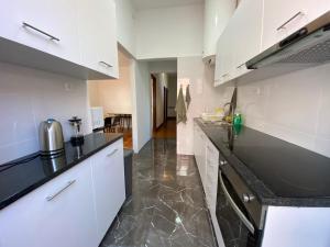 波尔图BREINER 54的厨房配有白色橱柜和黑色台面