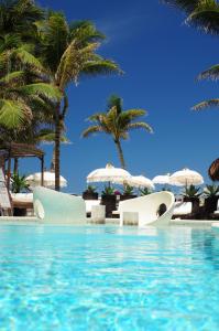 una piscina con 2 sillas y palmeras en El Taj Oceanfront and Beachside Condo Hotel, en Playa del Carmen