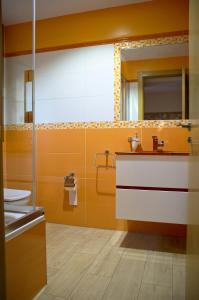 baño con paredes de color naranja, lavabo y espejo en casa oliva la bodegueta, en Abiego