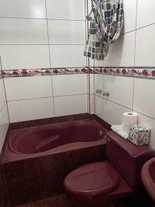 La salle de bains est pourvue de toilettes rouges et d'une baignoire. dans l'établissement Precioso e iluminado Rumah Premium_VES, à La Tablada