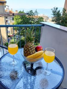 two glasses of orange juice and a bowl of fruit on a table at Amarena Apartment in Rijeka