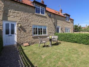 a brick house with a table and chairs in the yard at 8 Pottergate Mews in Helmsley