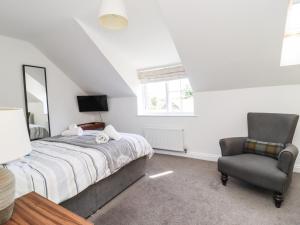 a bedroom with a bed and a chair at 8 Pottergate Mews in Helmsley