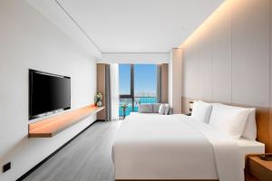 済南市にあるThe COLI Hotel Jinanの大型ベッド1台、薄型テレビが備わるホテルルームです。