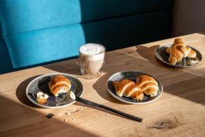 two plates of pastries on a table with a glass of milk at Base Aktivhotel Montafon in Sankt Gallenkirch