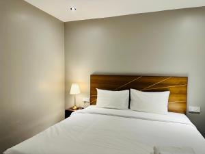 1 dormitorio con 1 cama blanca grande y cabecero de madera en The Bed Bukit Bintang en Kuala Lumpur