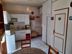 eine Küche mit weißen Schränken, einem Tisch und einer Tür in der Unterkunft Studio avec balcon amenage et wifi a Saint Gervais les Bains in Saint-Gervais-les-Bains