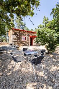 een tafel en stoelen voor een stenen huis bij Casa do Feitor - Douro - Quinta da Cabrida in Sendim