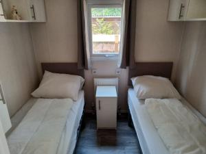 two beds in a small room with a window at Boshuis met grote tuin I Vakantiepark met Zwembad in Hoenderloo