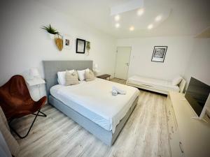 ein Schlafzimmer mit einem großen weißen Bett und einem Stuhl in der Unterkunft Cozy Place to Stay -Self check in 24h in Reşiţa
