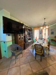 una sala da pranzo con tavolo, sedie e TV di Casa Ortu a Milis