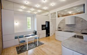 een keuken met witte kasten en een tafel met stoelen bij New Port Apartment Gdańsk in Gdańsk