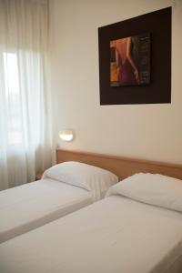 two beds in a hotel room with a picture on the wall at Albergo Aurora in Castenaso