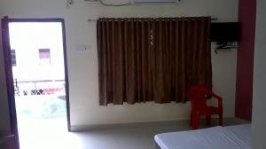 una camera da letto con un letto e una finestra con una sedia di St Xavier always a Chennai