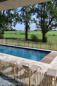 a swimming pool with two chairs and a fence at La Grange du Veld in Téteghem