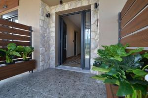 una puerta que conduce a un pasillo con plantas en Niel Holiday Apartments, Panel Hospitality Homes & Villas, en Leptokarya