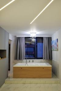 bañera grande en una habitación con ventana en BEAUTIFUL PEOPLE SUITES ATHENS ACROPOLIS VIEW, en Atenas 21 fotos más