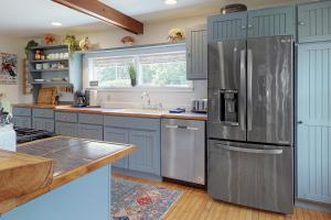 La cuisine est équipée de placards bleus et d'un réfrigérateur en acier inoxydable. dans l'établissement The Adams Mill Farm House, à Stowe