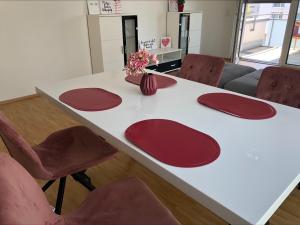 uma mesa com cadeiras vermelhas e uma mesa branca com um vaso sobre ela em Moderne Alpenblick Apartment em Friedrichshafen