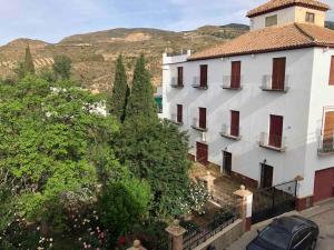 un gran edificio blanco con ventanas rojas y árboles en Apartamento Real 17, Cádiar, en Cádiar