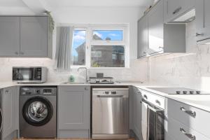 a white kitchen with a washing machine and a window at Brett Stays - Lower King Weston House in Avonmouth
