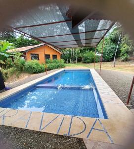 uma piscina com toldo em frente a uma casa em Manantial de Vida em Bejuco