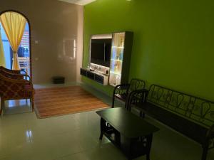 a living room with a green wall with a tv at 83 Homestay in Melaka