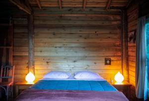 a bed in a wooden room with two lamps at Chalé Paiol - Sítio Lajinha in Alagoa