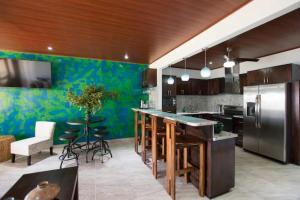 a kitchen with a refrigerator and a table with stools at Central located in Flamingo, Condo with gorgeous views - Flamingo Marina Resort in Playa Flamingo