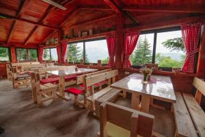 een eetkamer met houten tafels, banken en ramen bij Komovi - Kobil Do Guesthouse in Kolašin