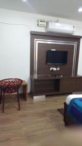 a living room with a tv and a chair at Hitech Shilparamam Guest House in Hyderabad