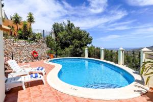 a swimming pool with two chairs and a patio with at Villa Monte Leon 7 in Atamaría