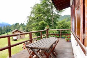 una terraza de madera con un banco de madera en una casa en * Chalet inside the nature* [12 guests + WI-FI], en Siror