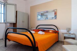 a bedroom with a bed with orange sheets and a mirror at Casa Vacanze da Nino in Torre Lapillo