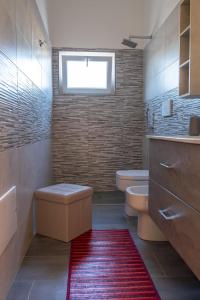 a bathroom with a toilet and a red rug at Casa Vacanze da Nino in Torre Lapillo