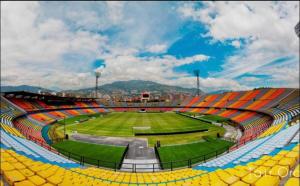 an empty stadium with yellow seats and a green field at Apartamento laureles Estadio Medellín 203 balcon in Medellín