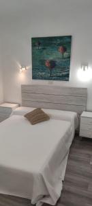a bedroom with a white bed with a painting on the wall at Chalet Sol y Sombra in Pals