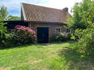 a brick house with a black door and some flowers at Holiday home Vossennest in Veere
