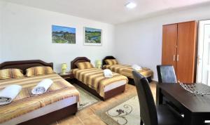 a room with three beds and a table and a desk at Apartmani Kljajevic Sutomore in Bar