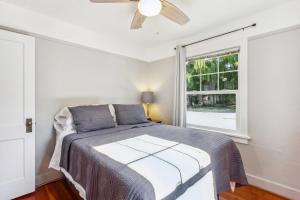 a bedroom with a bed with a ceiling fan and a window at Charming Eugene Retreat Private Hot Tub and Yard! in Eugene