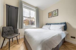 um quarto com uma cama, uma cadeira e uma janela em Central London Apartment em Londres