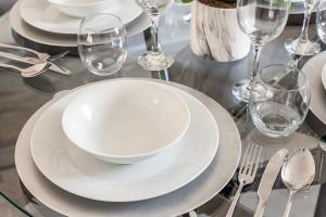 una mesa con platos blancos y copas de vino. en Deanery Court Vittrum Suites en Southampton