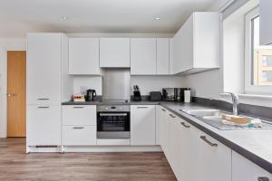 a white kitchen with white cabinets and a sink at Deanery Court Vittrum Suites in Southampton