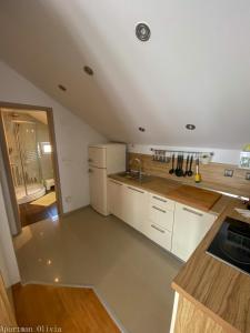 a kitchen with white cabinets and a white refrigerator at Apartman Olivia in Ludbreg