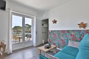 a living room with a blue couch and a balcony at Hotel du Cap in Capbreton