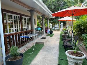 a patio with tables and chairs and an umbrella at Chloe's Cottage Self-Catering in La Digue