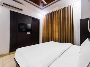 1 dormitorio con 1 cama y puerta con TV en OYO Hotel Br Villa, en Nārnaul